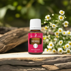 Ätherisches Öl Patchouli von Young Living, 100 % naturrein in Braunglasflasche mit Tropfer, auf Holz mit blühender Patchouli