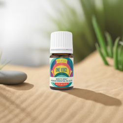 Ätherisches Öl One Voice von Young Living, 100 % naturrein in Braunglasflasche mit Tropfer, auf Sand in der Natur