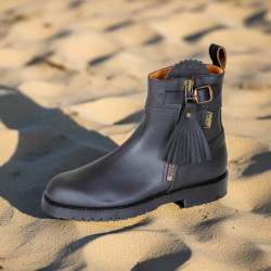 Spanische Reitstiefelette Bosque braun aus robustem Leder, Außenreißverschluss mit Bommel, Seitansicht, im Sand