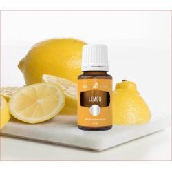 Ätherisches Öl Zitrone 100 % naturrein in 15ml Braunglasflasche mit Tropfer, auf Marmorplatte mit Zitronen im Hintergrund